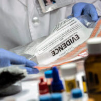 Police specialized taking sample of a bag of evidence in forensic laboratory, conceptual image